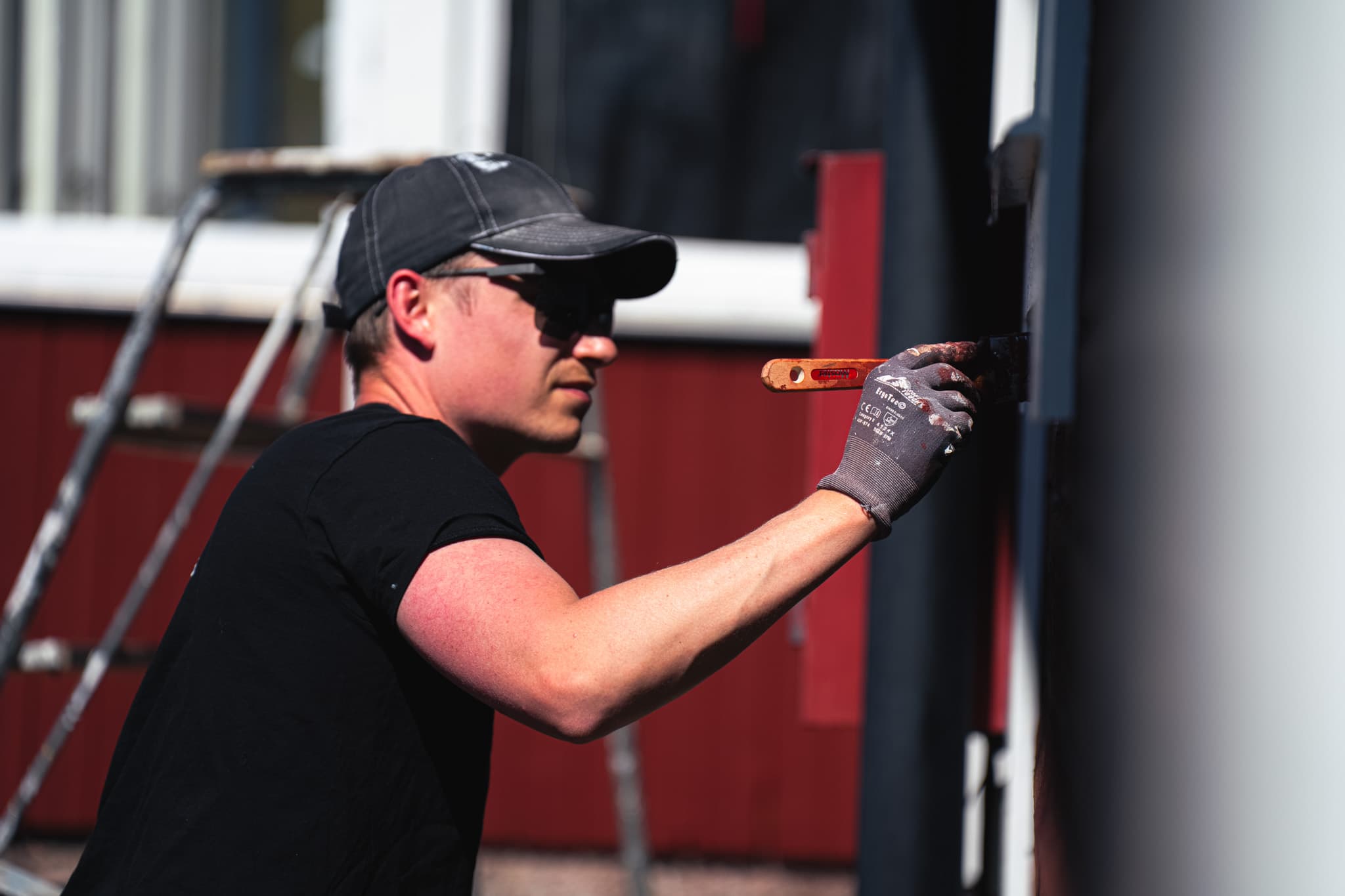 Fönstermålning – målare målar fönsterbåge på rött hus