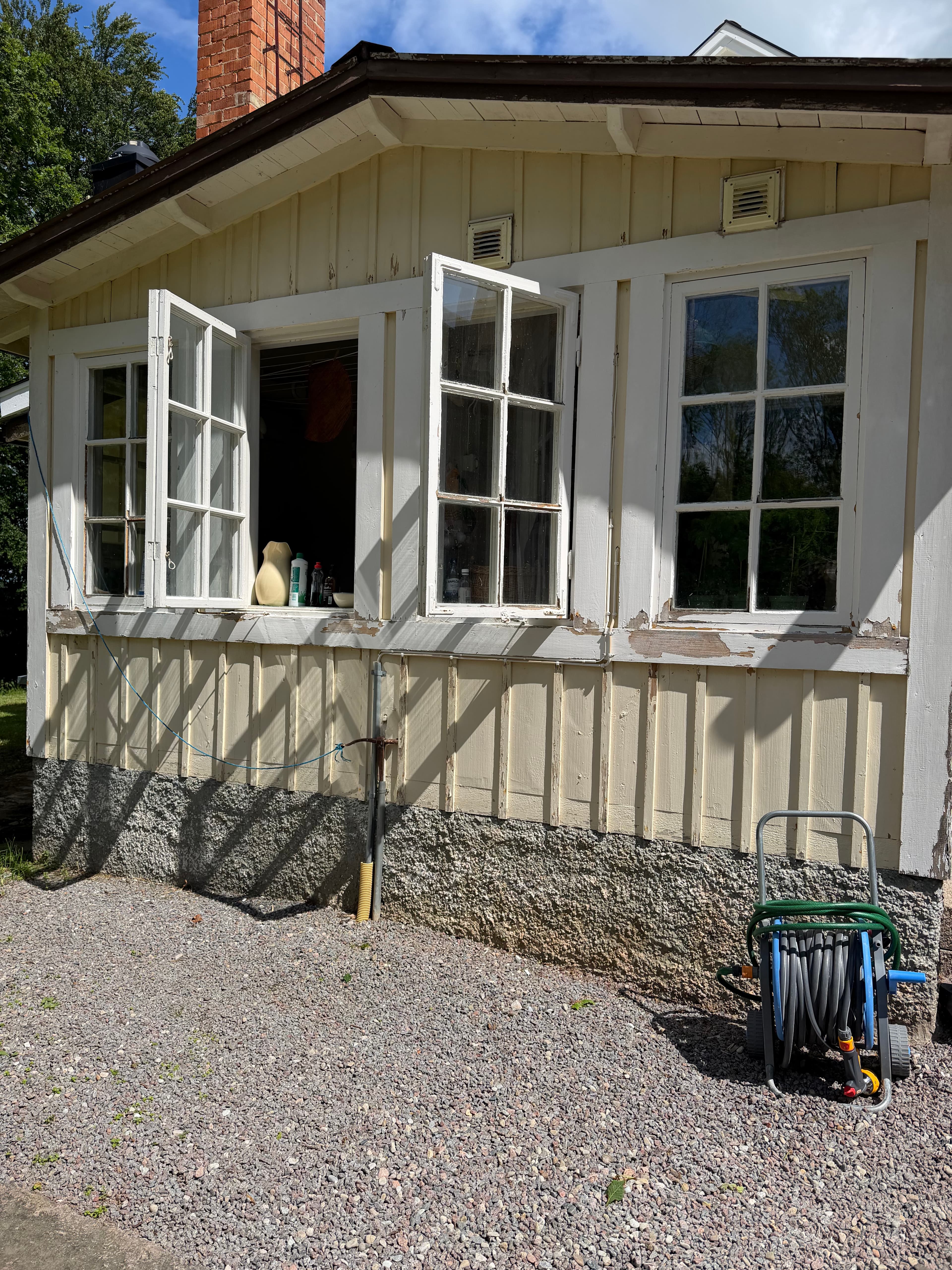 Inglasad veranda i Linköping före fasadmålning – flagnande vit färg och gråtnat trä